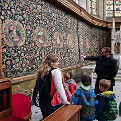 Pater Ulrich. zeigt den Kindern den Wandteppich von Frater Benno Haan